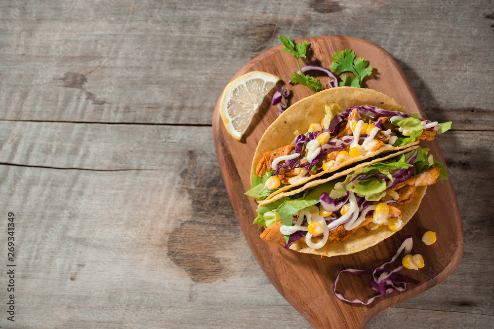 Traditional mexican taco with chicken and vegetables on wooden table. Latin american food.