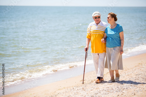  Senior Couple Walking Along Beach Together