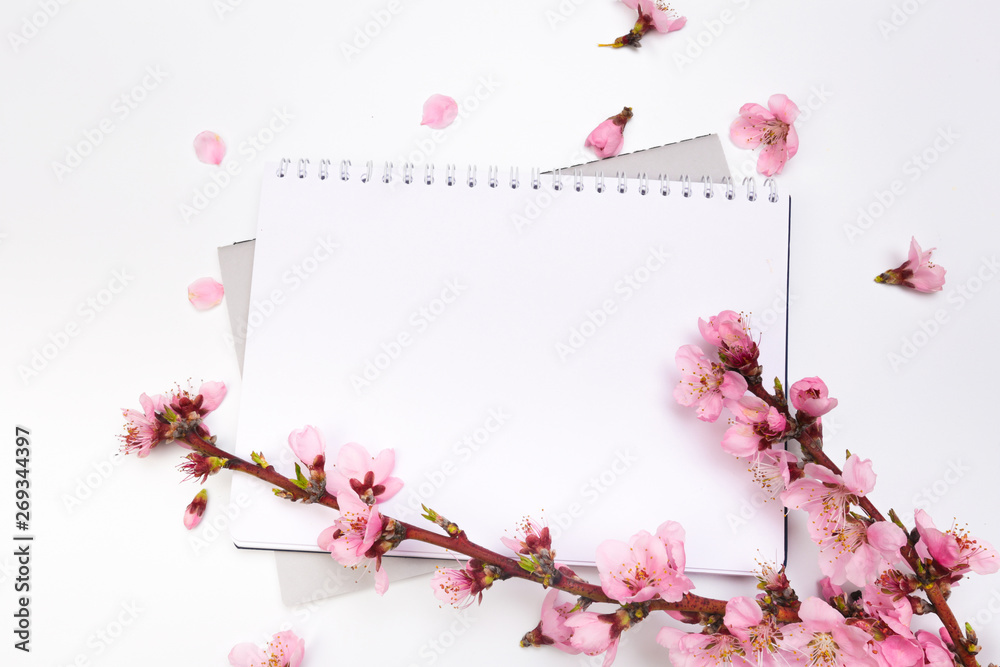 mock up notebook and sprigs of the apricot tree with flowers on white background . Place for text. The concept of spring came, happy easter, mother's day.Top view.Flay lay.