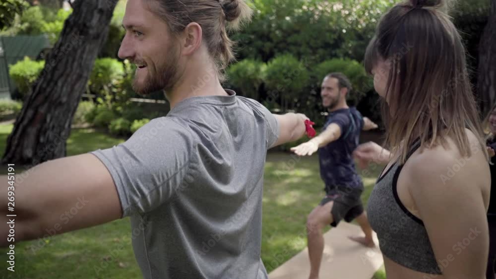 Female yoga trainer exercising with people in park. Smiling young woman helping men practicing yoga outdoor. Yoga concept Female yoga trainer exercising with people in park. Smiling young woman helping men practicing yoga outdoor. Yoga concept