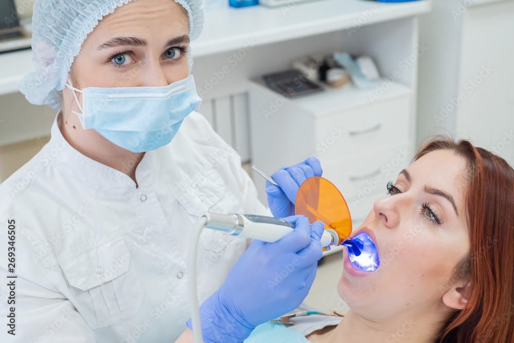 Female dentist fixed and dry dental fillings with light. Beautiful