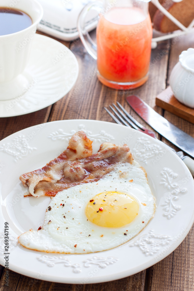 Breakfast of fried eggs with bacon on a wooden table, selective focus
