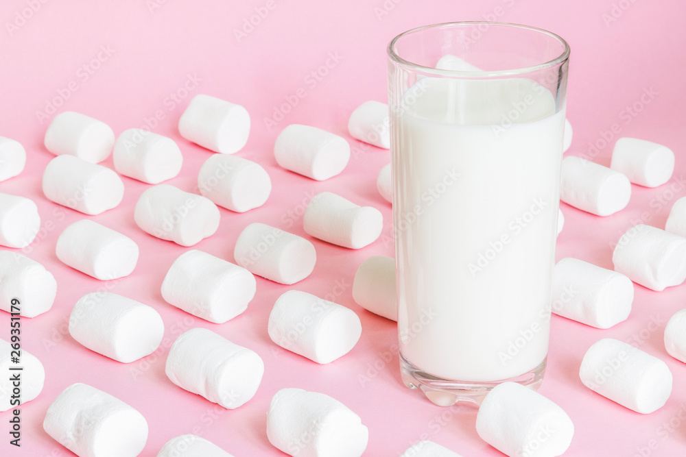 White marshmallows and glass with milk on pink background White marshmallows and glass with milk on pink background