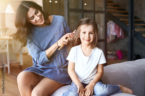 Mother brushing hair of her...