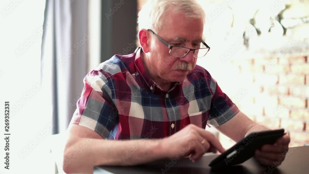 Senior man reading something on e-book at home Senior man reading something on e-book at home