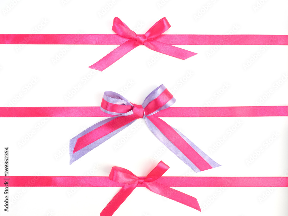 Three pink satin ribbon bows on white background. One bow of two pink and lilac ribbons