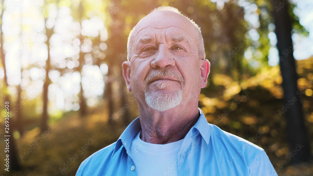 Portrait of senior man with a beard smiling while standing outside in sunlight. Portrait of senior man with a beard smiling while standing outside in sunlight.