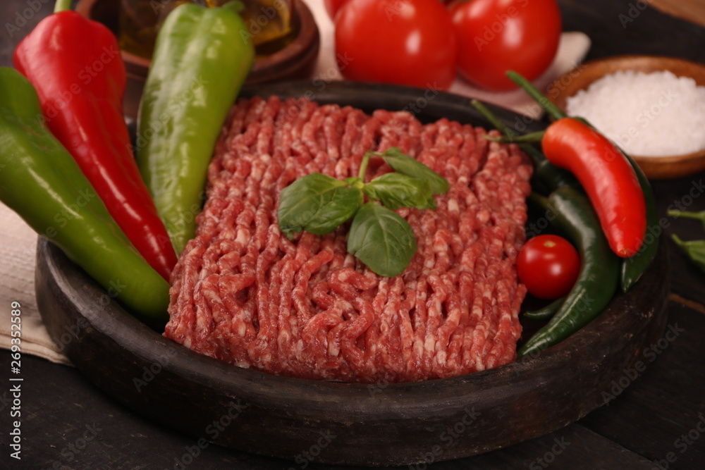 raw minced meat on plate, ingredients for burger with tomato, pepper, onion, spices and seasonings on black background. raw minced meat on plate, ingredients for burger with tomato, pepper, onion, spices and seasonings on black background.