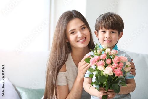 Happy mother and son with bouquet of flowers at home