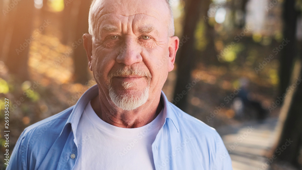 Portrait of senior man with a beard smiling while standing outside in sunlight. Portrait of senior man with a beard smiling while standing outside in sunlight.
