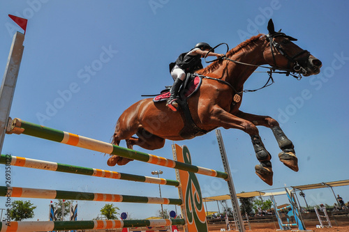 The bottom view of the rider on horse jumping over a hurdle during the equestrian event