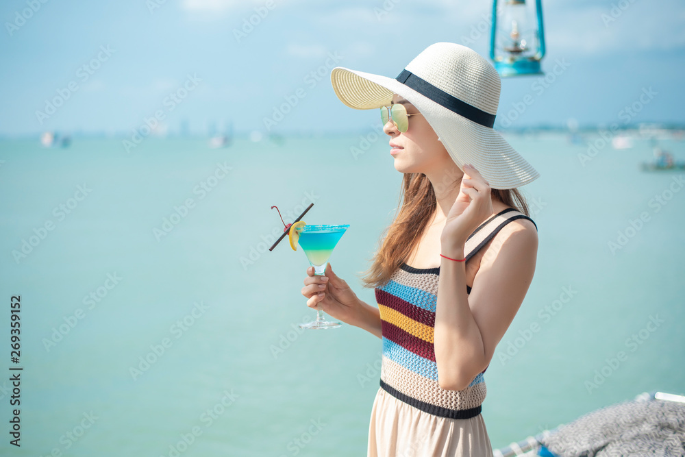 Fototapeta premium Beautiful woman is drinking ice summer drink in the beach, summer concept