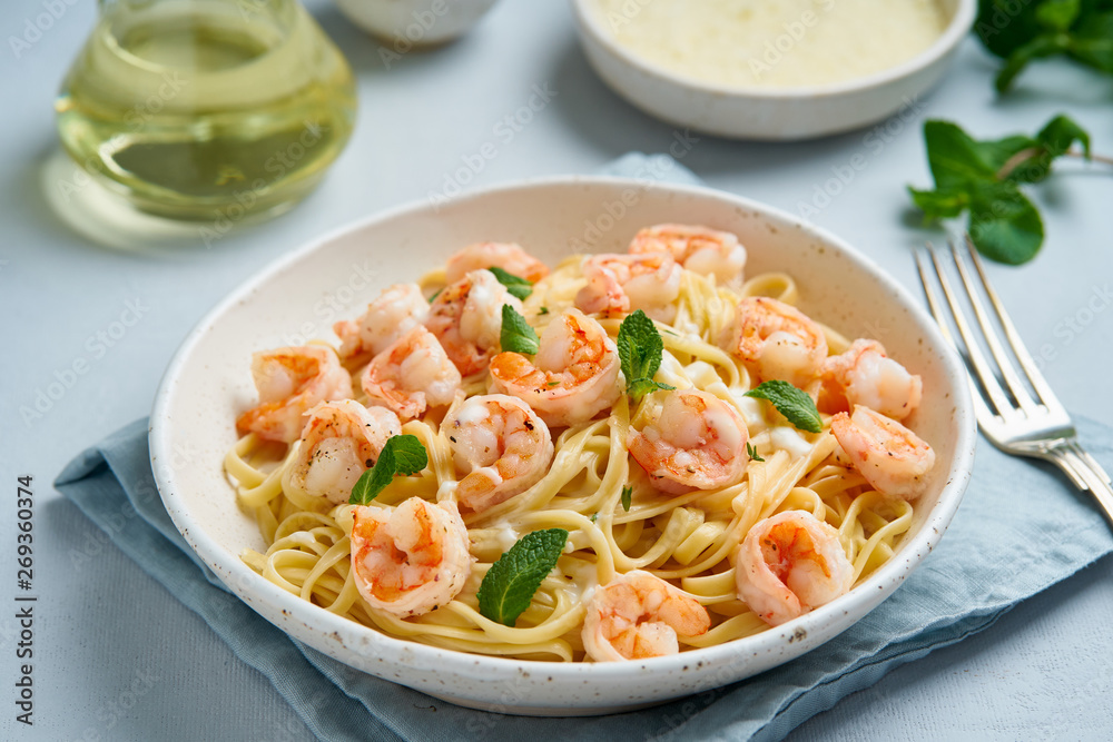 Pasta spaghetti with roasted shrimps, bechamel sauce, mint leaf on blue table, italian cuisine, side view Pasta spaghetti with roasted shrimps, bechamel sauce, mint leaf on blue table, italian cuisine, side view