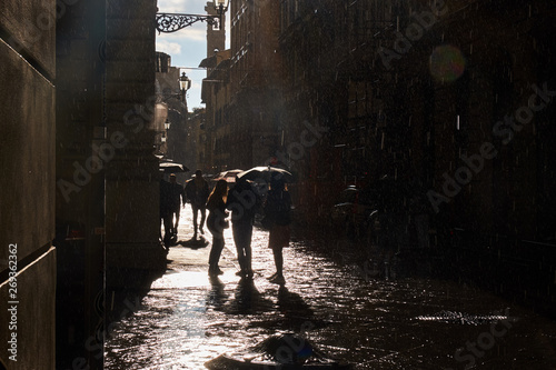 Three girls under umbrella sun after rain 