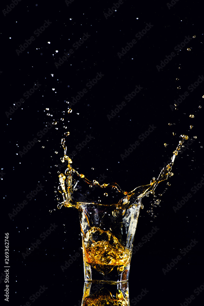 Isolated shot of whiskey with splash on black background, brandy in a glass Isolated shot of whiskey with splash on black background, brandy in a glass