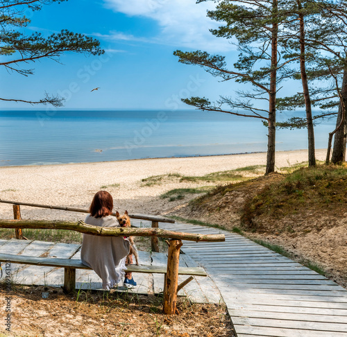 Happy woman with a dog at resting point near sandy beach of the Baltic Sea