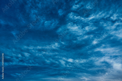 Concept photo of a blue sky background with feather clouds on a sunny day with a dry sun.
