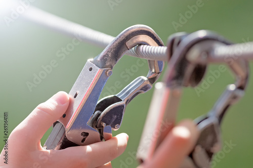 person locked safety hook on rope by hand closeup view of hiking equipment isolated on blur background security protection device outdoor sport activity and industry work authentic lifestyle concept