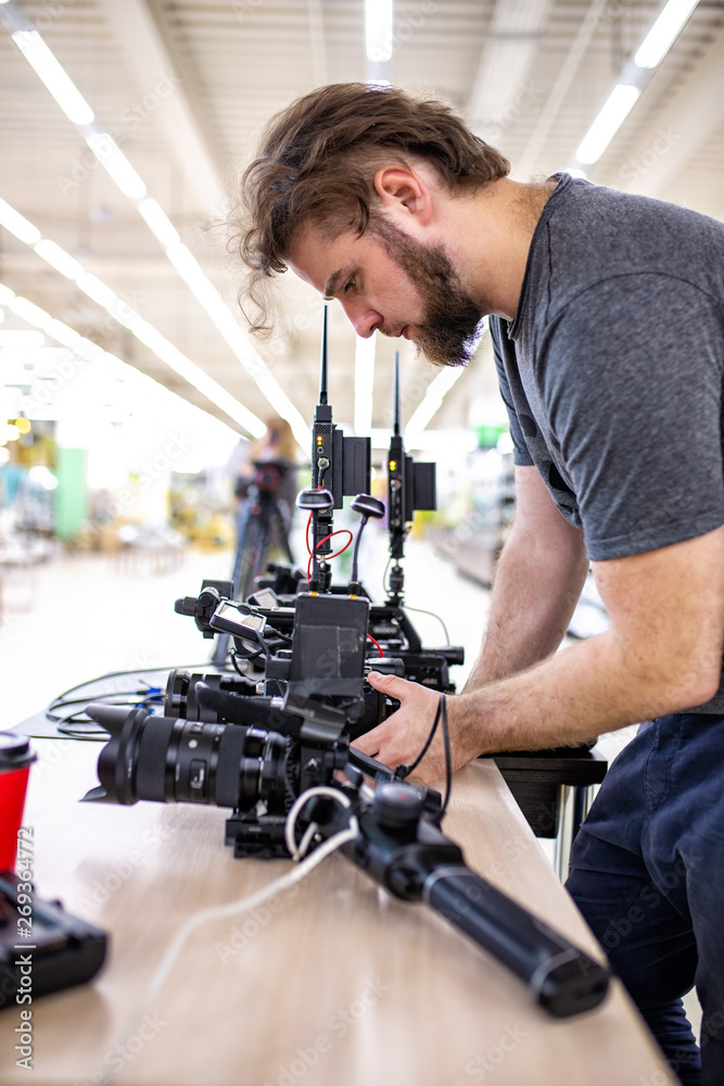 Videographer shooting a film or a television program in a studio with a professional camera, backstage Videographer shooting a film or a television program in a studio with a professional camera, backstage