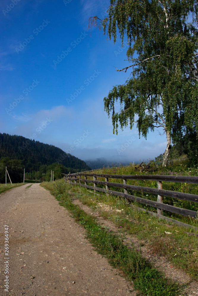 Summer landscape the old dusty road to the mountains.