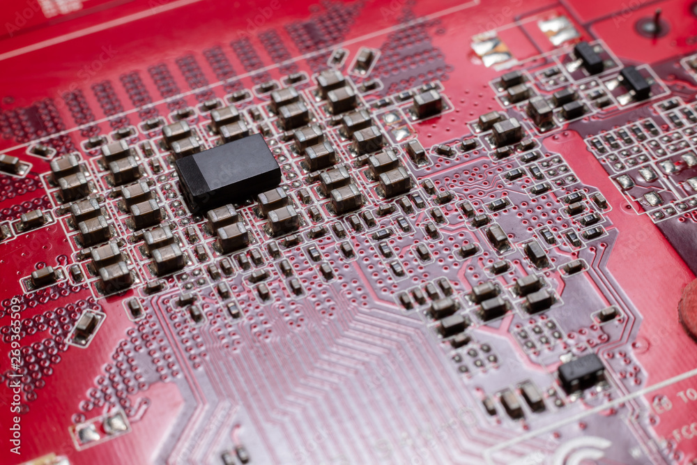 Transistors from the back of the video card under the graphic core. Macro shooting of a red microcircuit. The concept of a microscopic city.