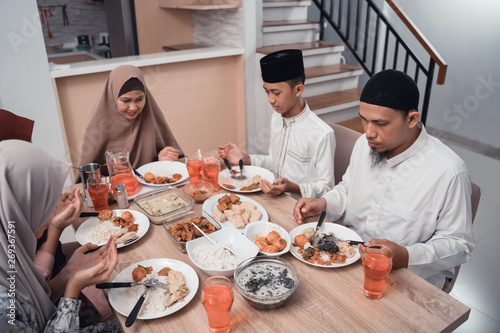 muslim family together pray before meals, a fast breaking meal served on a table