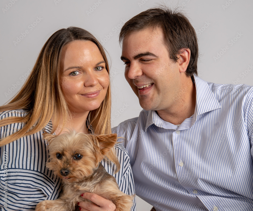 Young couple pose in a photography studio with his yorkshire dog. Young couple pose in a photography studio with his yorkshire dog.