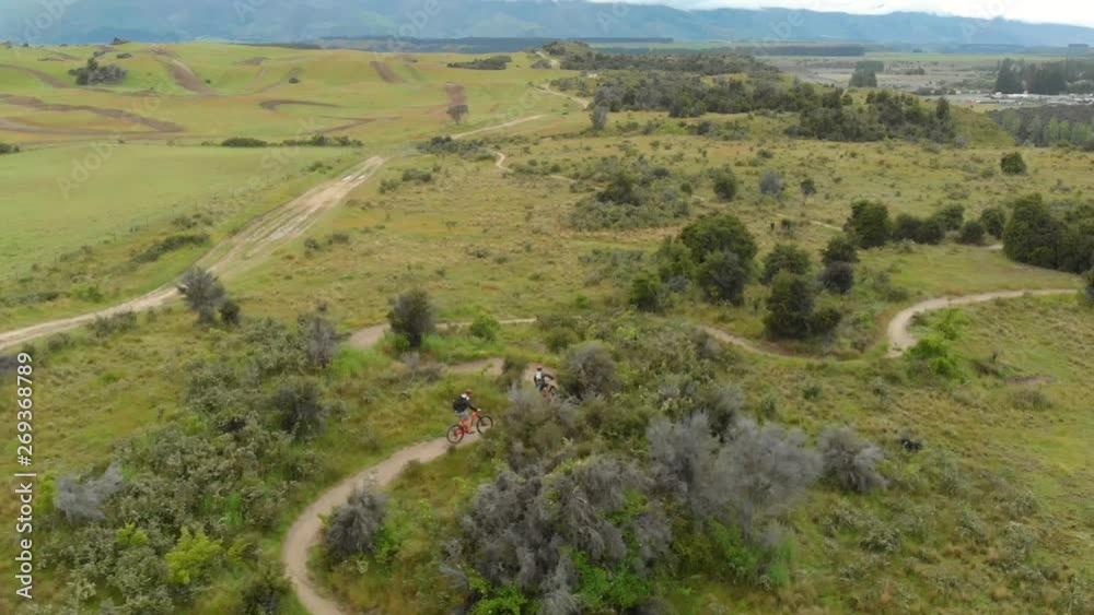 Aerial drone tracking shots of two cyclists riding mountain bikes on a track in a field Aerial drone tracking shots of two cyclists riding mountain bikes on a track in a field