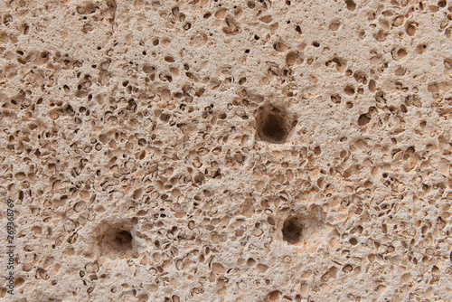 Beige concrete old wall with many small holes. Rough abstract texture. 