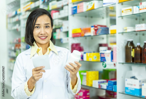 Pharmacist Asian female filling prescription medication in pharmacy for customer or patient. small business, medicine, pharmaceutics, health care, lifestyle and people concept