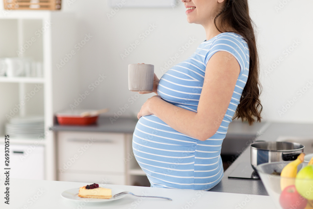pregnancy, people and expectation concept - close up of pregnant woman with cup of tea at home kitchen pregnancy, people and expectation concept - close up of pregnant woman with cup of tea at home kitchen