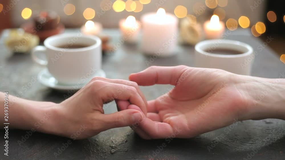 A loving couple hold hands at a romantic table with candles. 