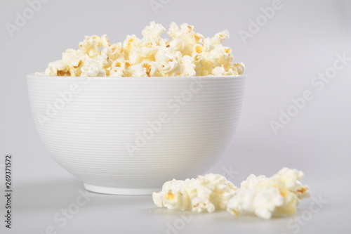 Caramel popcorn in white bowl on white background.
