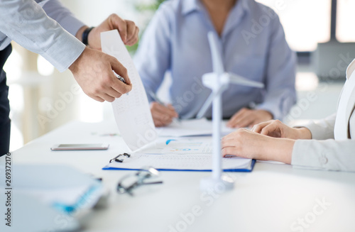business and people concept - businesswoman showing clipboard with financial report to colleagues at office