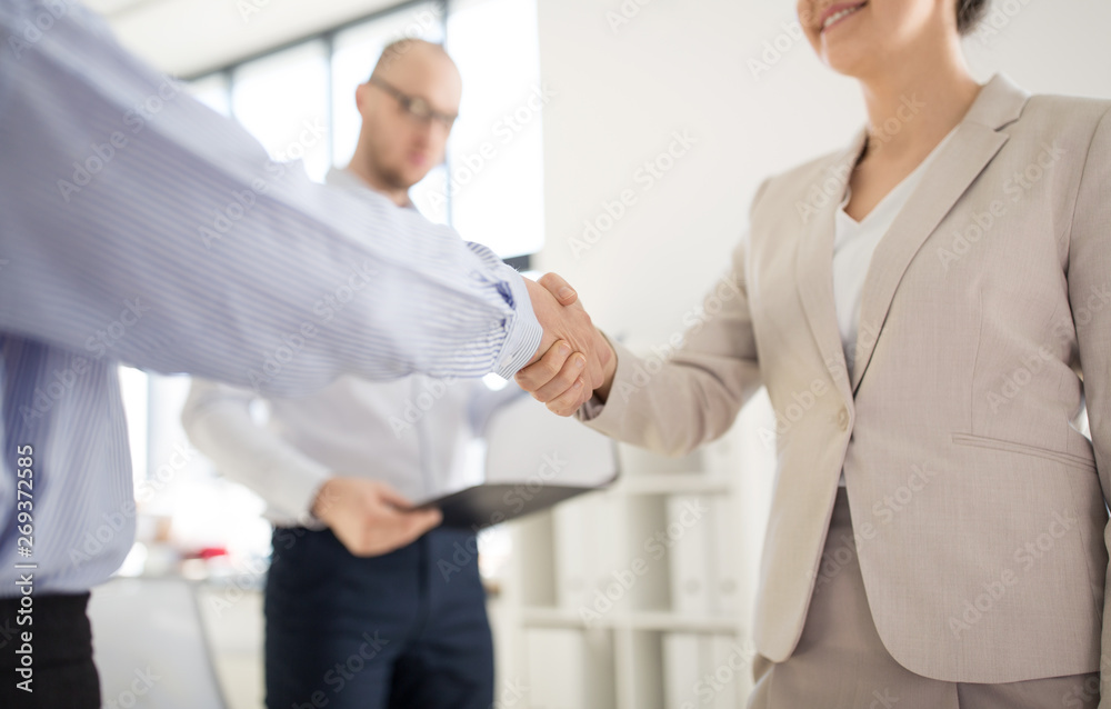 cooperation, collaboration and partnership concept - close up of business partners making handshake at office cooperation, collaboration and partnership concept - close up of business partners making handshake at office