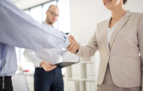 cooperation, collaboration and partnership concept - close up of business partners making handshake at office