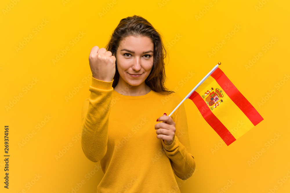 Young european woman holding a spanish flag showing fist to camera, aggressive facial expression. Young european woman holding a spanish flag showing fist to camera, aggressive facial expression.