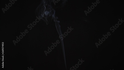 A thin trail of smoke rising across the screen, shot backlit on black background.