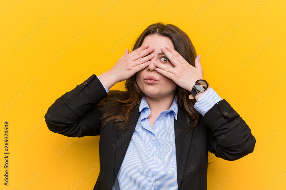 Young plus size caucasian business woman blink through fingers frightened and nervous. Young plus size caucasian business woman blink through fingers frightened and nervous.