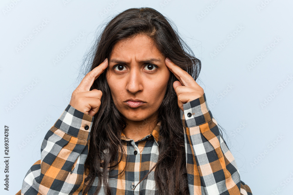 Young cool indian woman focused on a task, keeping him forefingers pointing head. Young cool indian woman focused on a task, keeping him forefingers pointing head.