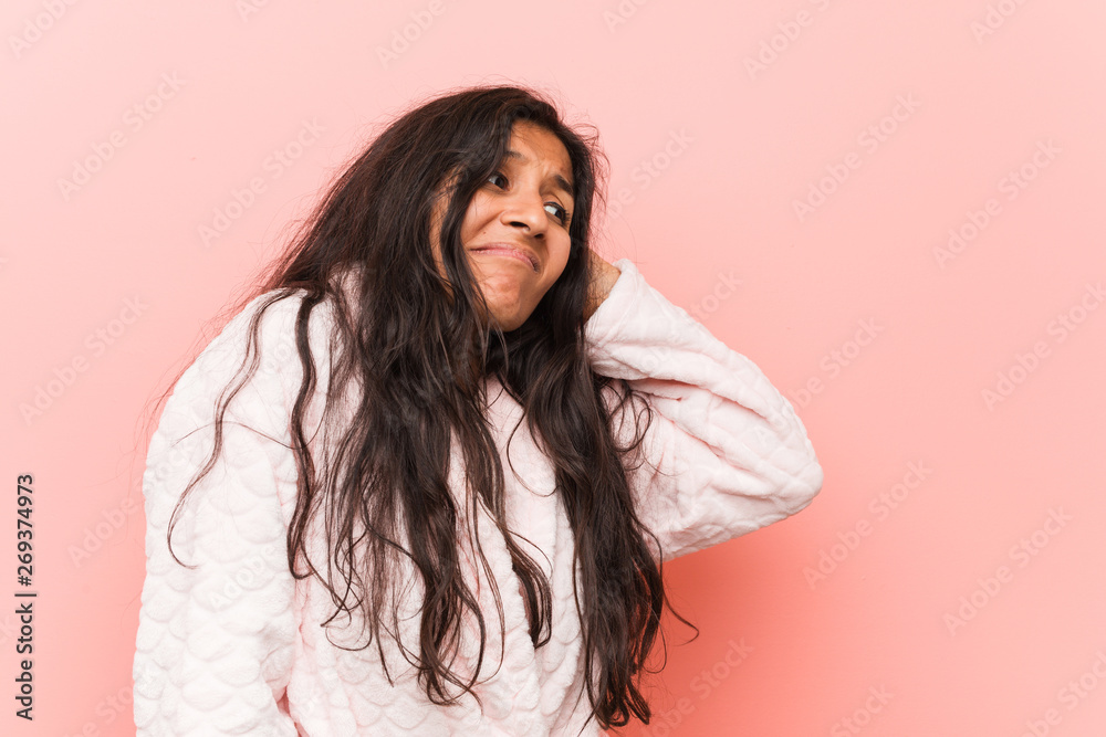 Young indian woman wearing pajama touching back of head, thinking and making a choice. Young indian woman wearing pajama touching back of head, thinking and making a choice.