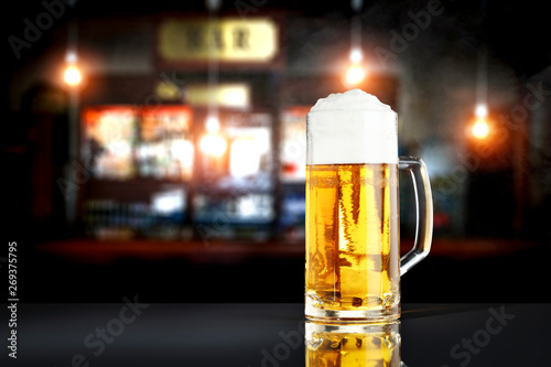 Cold fresh beer in glass on wooden table and free space for your decoration. Blurred bar interior 