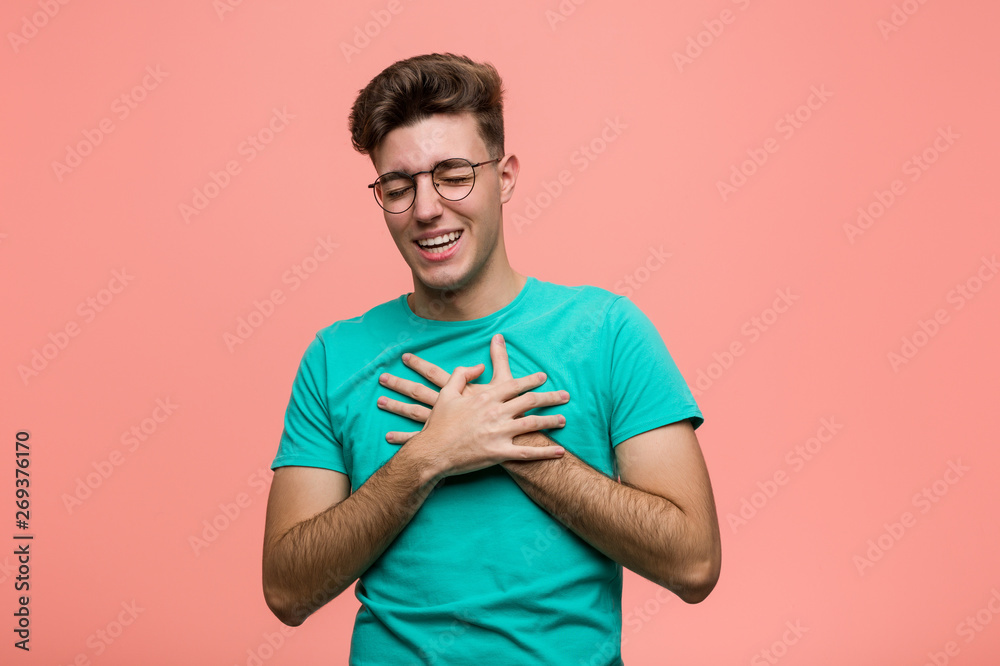 Young cool caucasian man laughing keeping hands on heart, concept of happiness. Young cool caucasian man laughing keeping hands on heart, concept of happiness.