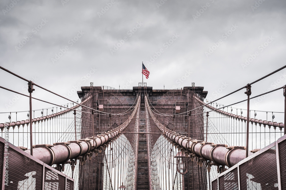 Fototapeta premium Imerssive dramatic landscape of the architecture of the famous Brooklyn Bridge in New York under a contrasting stormy sky - New York City, NY