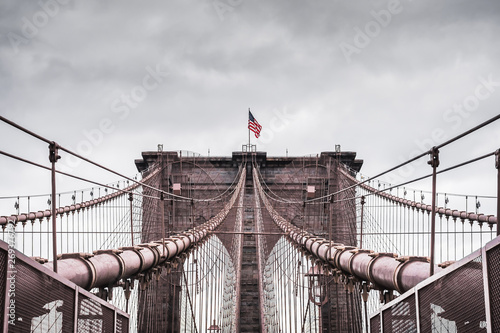 Imerssive dramatic landscape of the architecture of the famous Brooklyn Bridge in New York under a contrasting stormy sky - New York City, NY