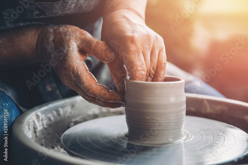 Obraz na płótnie Wrinkled hands wizard on potter wheel makes clay dishes