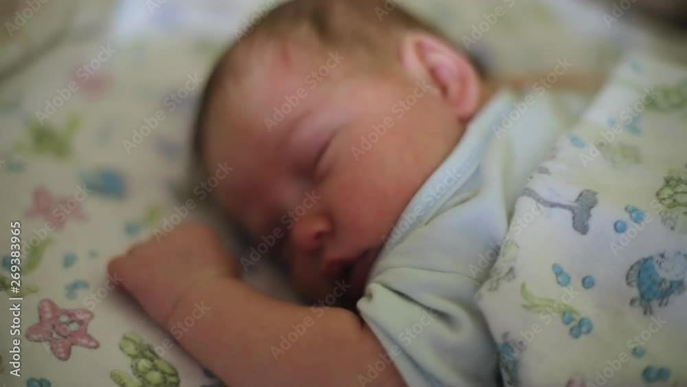 Close-up of lovely cute newborn child moving while sleeping in the bed. Portrait of adorable sleepy kid. Close-up of lovely cute newborn child moving while sleeping in the bed. Portrait of adorable sleepy kid.