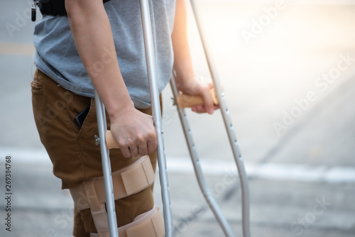 Tela Disabled woman with crutches or walking stick or knee support standing in back side,half  body