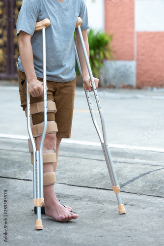 Disabled woman with crutches or walking stick or knee support standing in back side,full lenght body Fototapeta