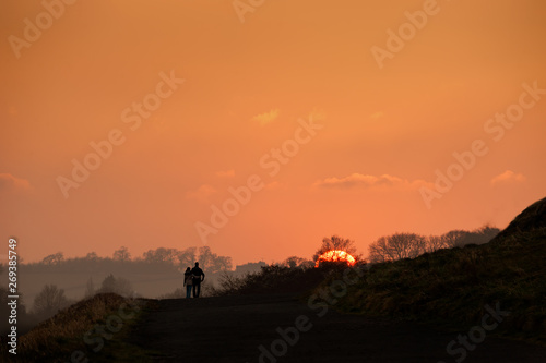 A man and woman couple walking at sunset. © cornfield